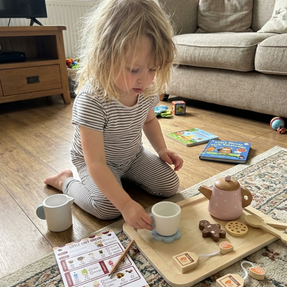 Child playing with a tea set on the floor in a living room with Little Cafe Role Play notepad