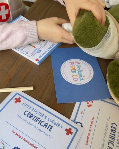 Children playing with a toy doctor set on a table with certificates and a pretend paper co notepad